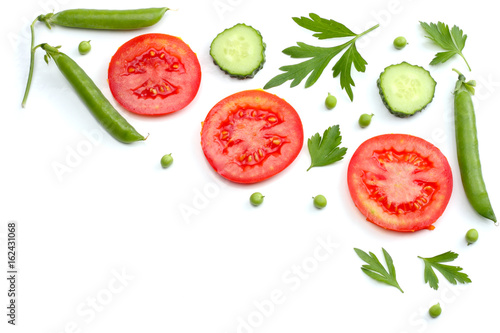 sliced tomatoes, sliced carrot, sliced cucumber, parsley and fresh green peas isolated on a white background. top view