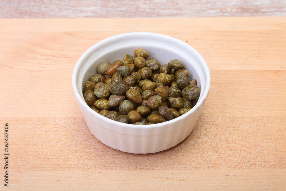 bowl with fresh capers on wooden table bowl with fresh capers on wooden table