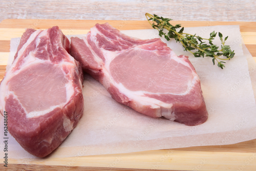 Raw pork chops, spices and rosemary on cutting board. Ready for cooking. Raw pork chops, spices and rosemary on cutting board. Ready for cooking.