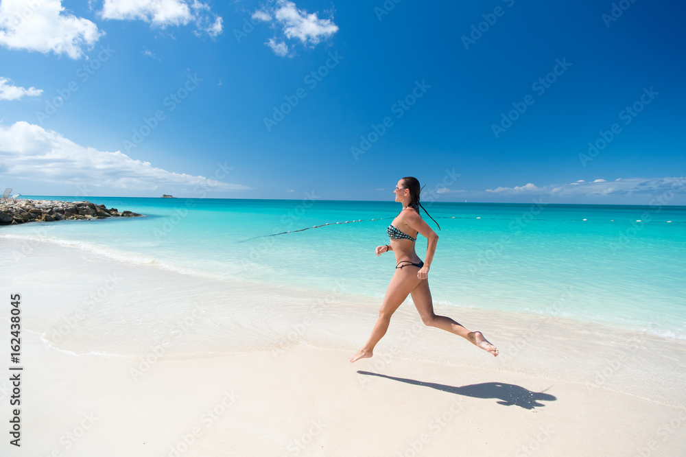 Young woman running at the tropical beach