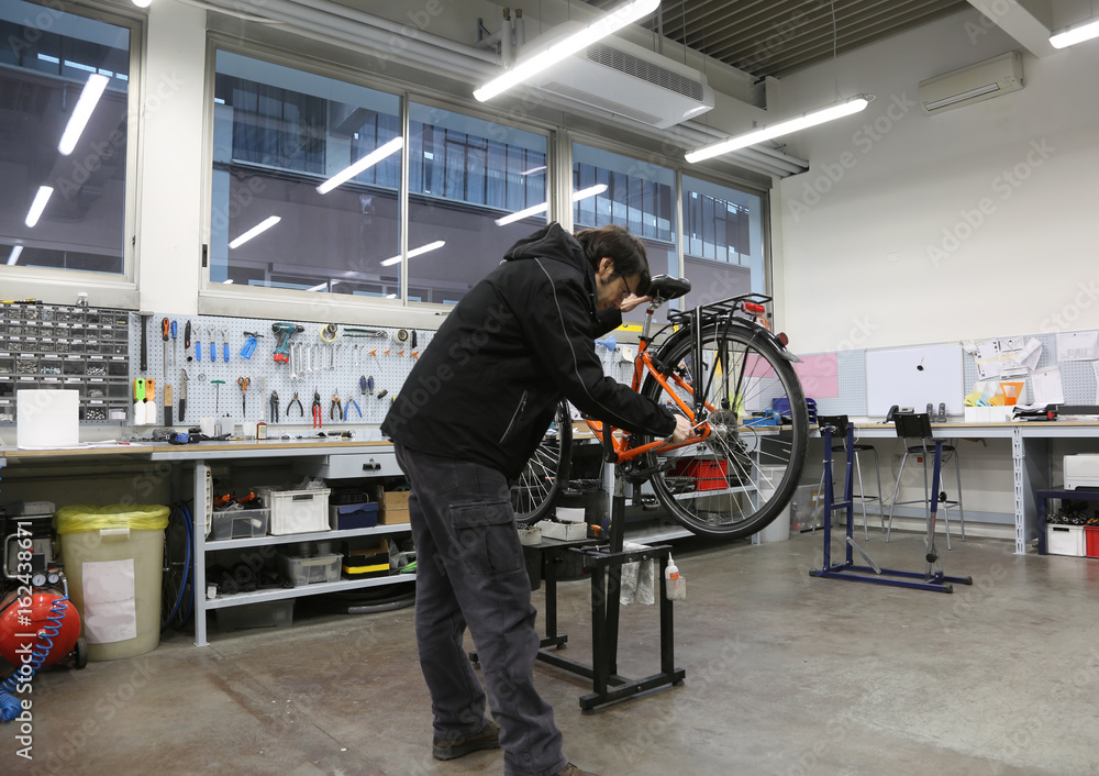 Young mechanic repairing the wheel of the bicycle inside the mec