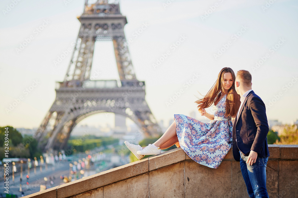Beautiful loving couple sitting near the Eiffel tower in Paris