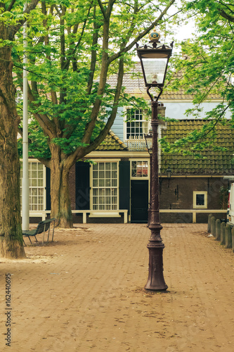 Old house in Amsterdam, a lantern and trees in the foreground. May 2017.