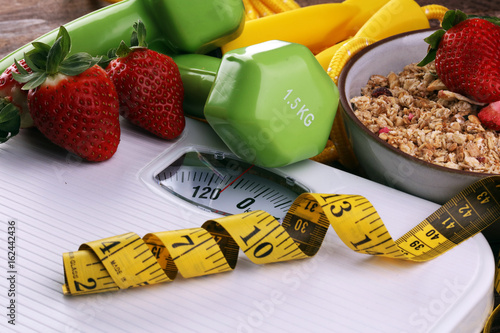 scale with cereals, skipping rope, fruit, strawberry, weight and tape measure and concept of diet and healthy lifestyle photo