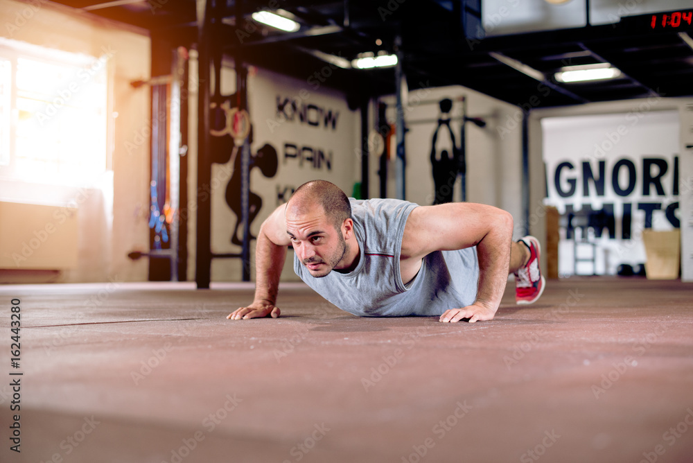 Fototapeta premium Man is doing push ups in rustic gym