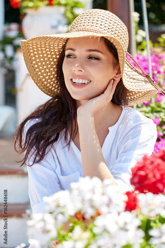 Young pretty woman smiling. Beautiful women in a straw hat at the summer garden.