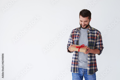 Portrait of a smiling casual man looking at gift box