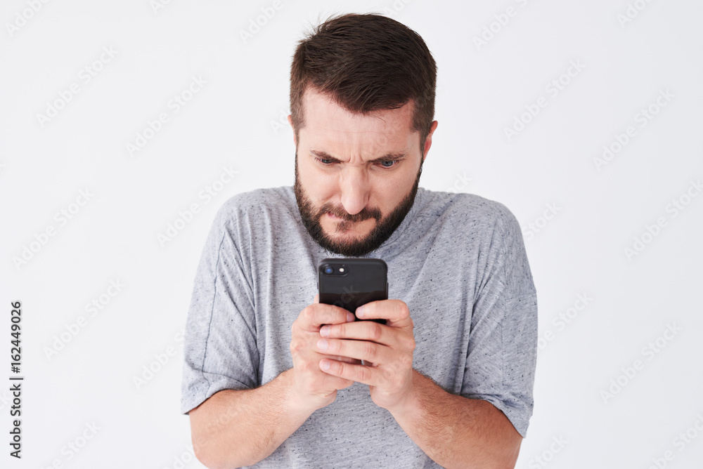 Excited bearded man in checked shirt playing on smartphone Excited bearded man in checked shirt playing on smartphone