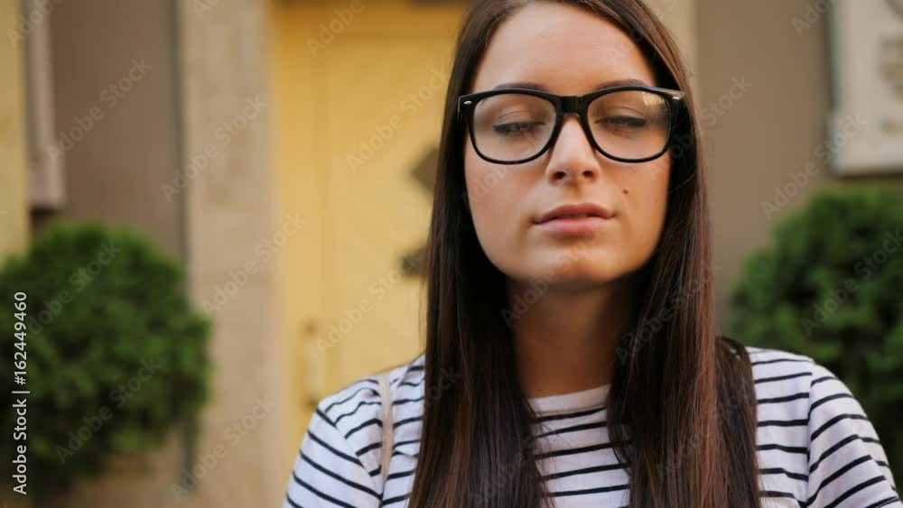 Young attractive woman wearing glasses smiling while standing outside in the city street. Yellow doors background. Portrait shot. Close up Young attractive woman wearing glasses smiling while standing outside in the city street. Yellow doors background. Portrait shot. Close up