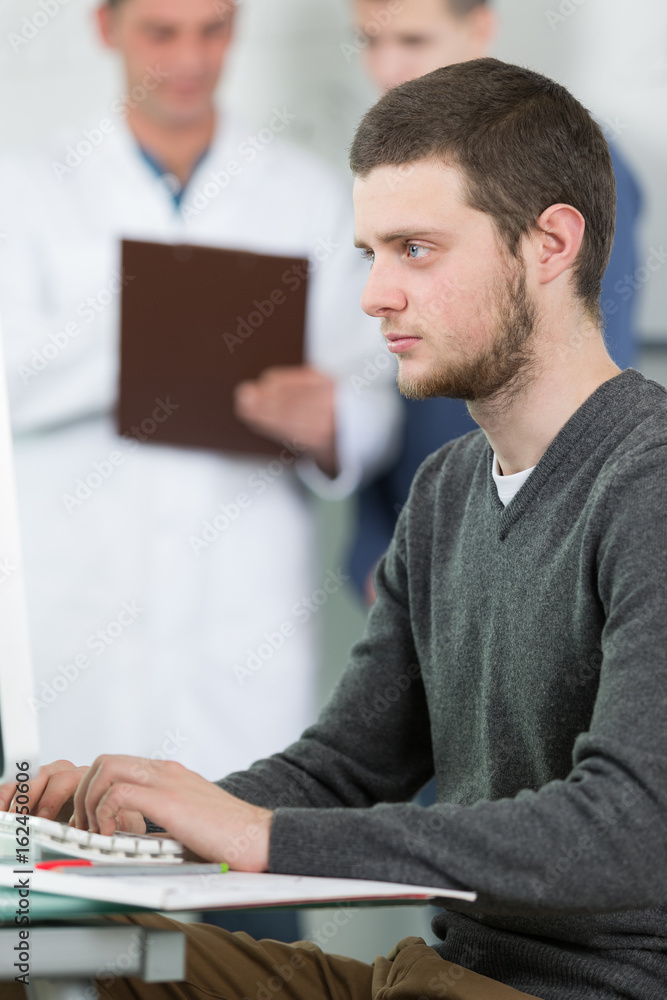 male student in classroom doing homework on computer in classroom male student in classroom doing homework on computer in classroom