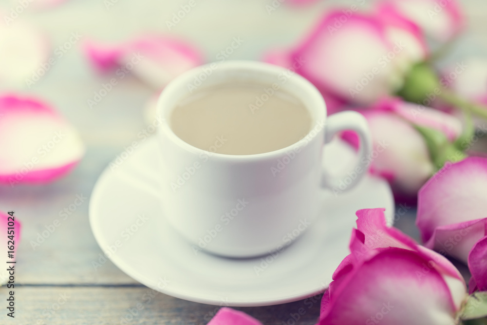 Cup of coffee on rustic wooden table in a frame of pink roses. Greeting card with flower. Soft focus. Cup of coffee on rustic wooden table in a frame of pink roses. Greeting card with flower. Soft focus.
