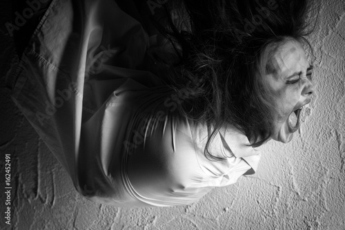 Canvas Print screaming crazy woman with flying hair in straitjacket, monochrome