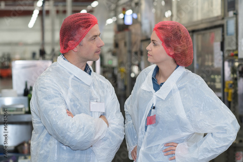 Картината върху платно biologist team talking and wearing hairnet in the factory
