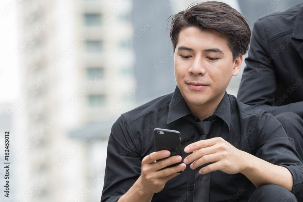Smart young business man is smiling when checking message in his mobile phone Smart young business man is smiling when checking message in his mobile phone