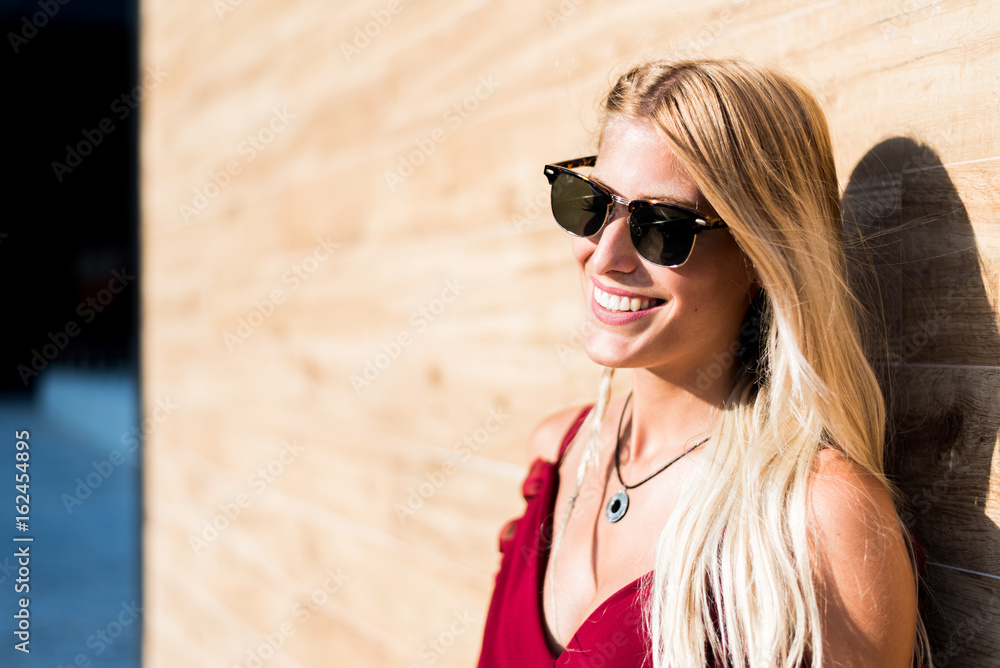 happy beautiful blonde woman wearing sunglasses smiling in a wood wall happy beautiful blonde woman wearing sunglasses smiling in a wood wall