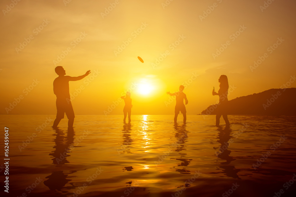 Silhouette of people playing at the beach in sunset