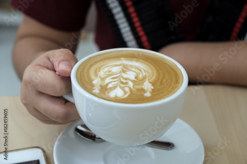 woman holding hot cup of latte coffee