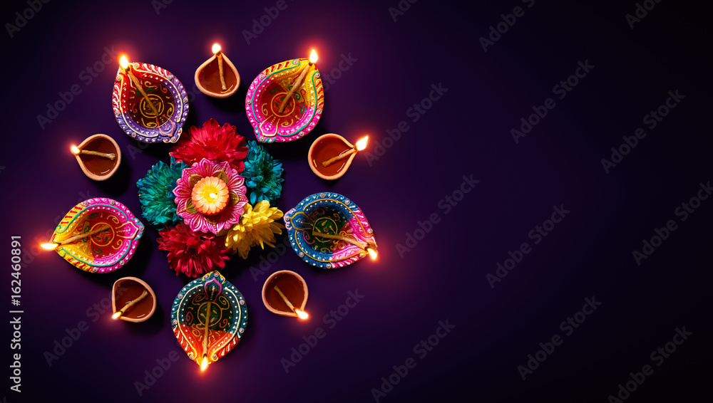 Fototapeta premium Colorful clay diya lamps with flowers on purple background