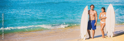 Beach surfing vacation banner surfers people fitness lifestyle couple with surfboards ready to surf on blue ocean background. Summer travel holidays.