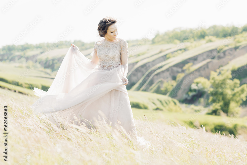 fine art wedding photography. Beautiful bride with bouquet and dress with train in nature