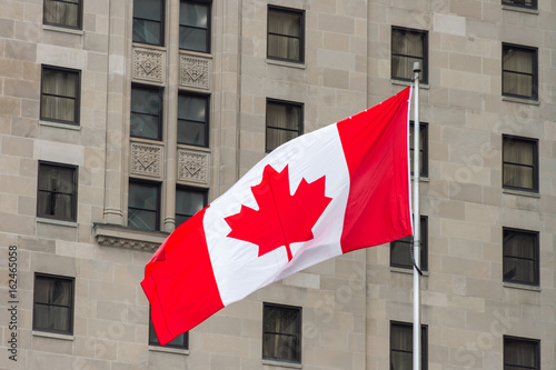 Big Canada flag waving in the wind with a wall in the background