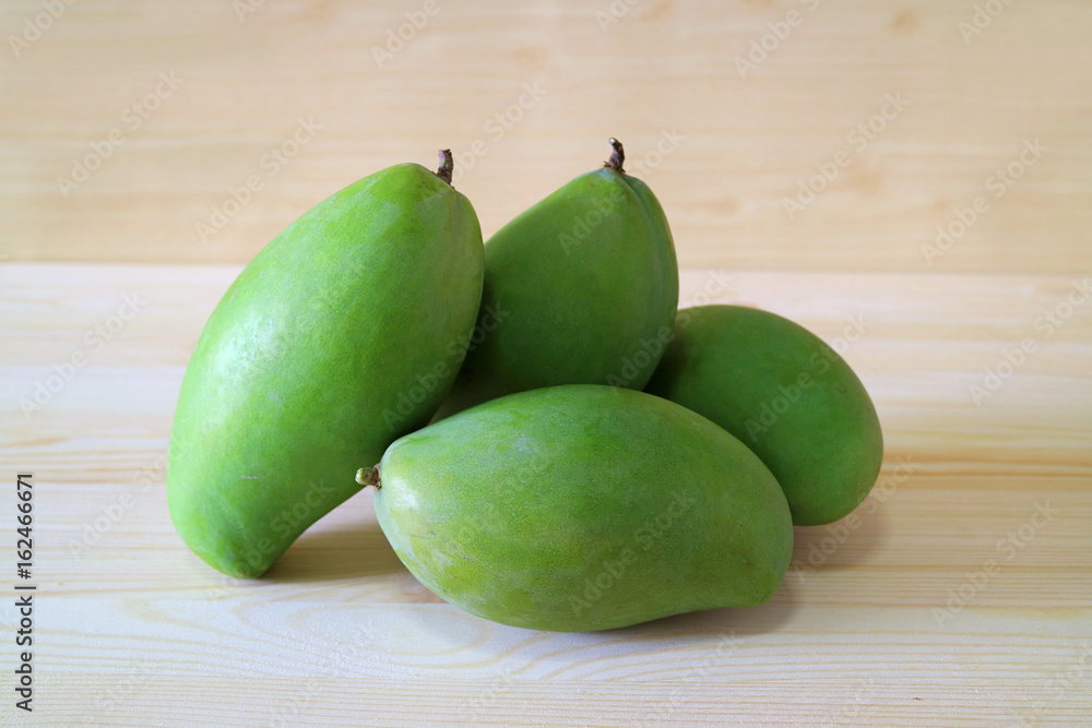 Pile of Vibrant Green Color Young Mangoes on the Wooden Table, Thailand Pile of Vibrant Green Color Young Mangoes on the Wooden Table, Thailand