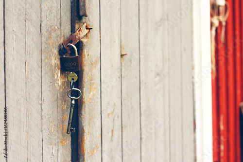 Old rusty padlock with keys on wooden barn door