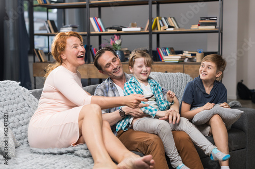 Family Sitting On Couch Watching TV  Happy Smiling Parents Spending Time With Children In Living Room
