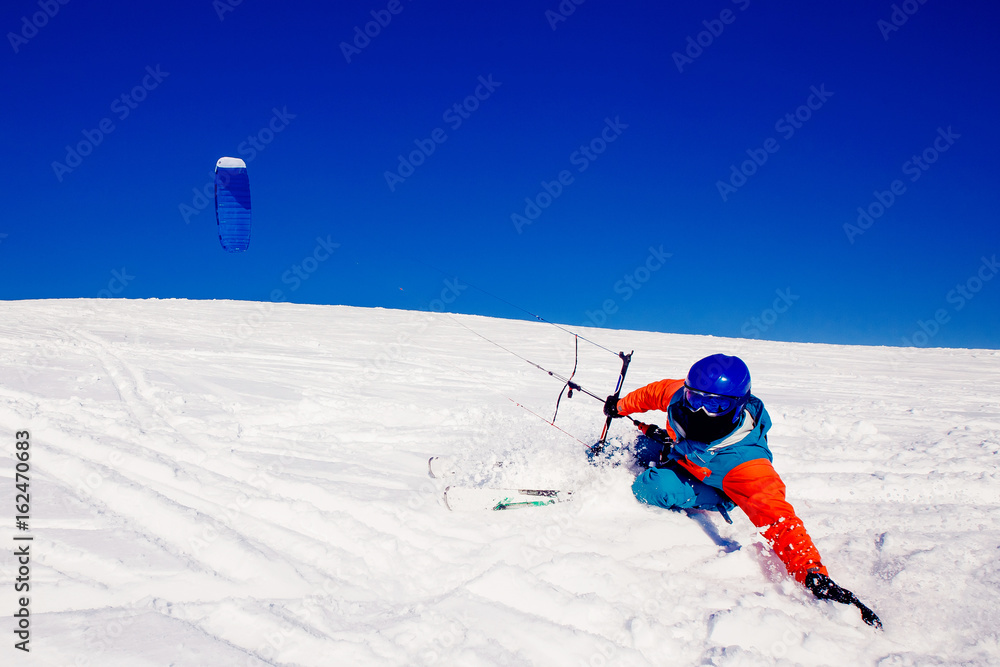  Skier with a kite on fresh snow in the winter in the tundra of Russia against a clear blue sky. Teriberka, Kola Peninsula, Russia. Concept of winter sports snowkite on ski.