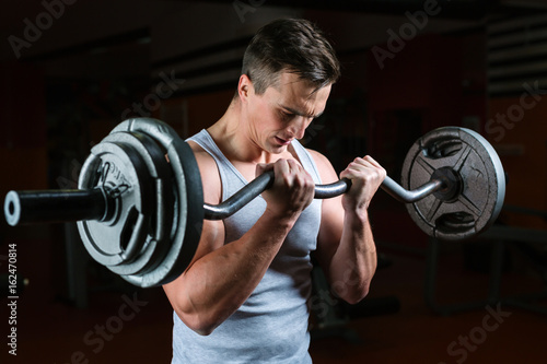 Closeup portrait of a muscular man workout with barbell at gym. Deadlift barbells workout.
