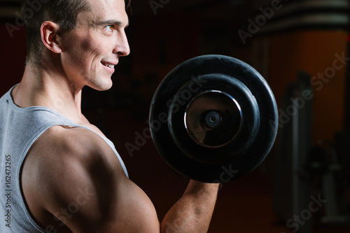 Closeup portrait of a muscular man workout with barbell at gym. Deadlift barbells workout.