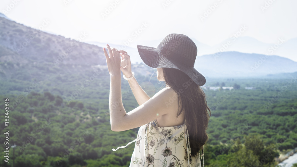 Woman traveler photographing beautiful natural view mountains on the island of Crete. Concept - tourism, travel, photos from vacation