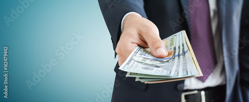 Businessman giving money,   united states dollar (USD) bills, on gray background