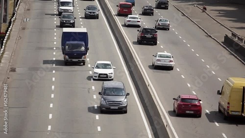 Transport traffic on two-way road on a sunny day, panoramic view from above, highway perspective. A two-lane road with six lanes of traffic each way.
