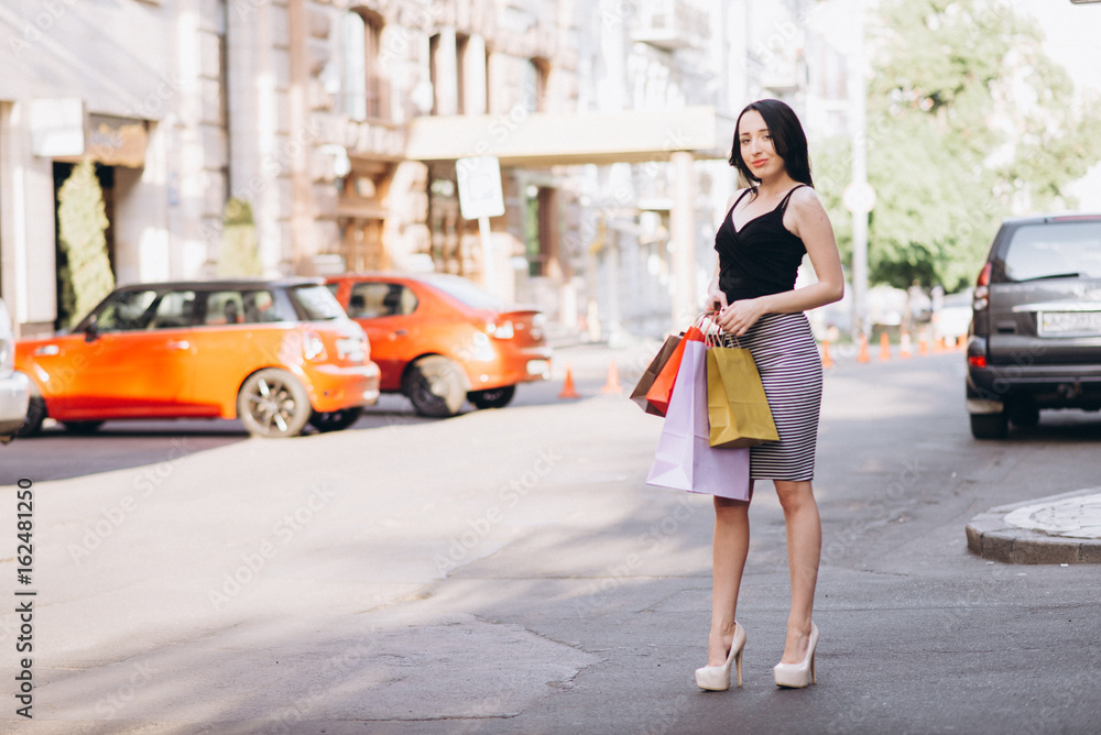 Fashionably dressed woman with colored shopping bags, shopping concept