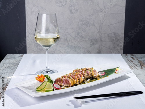 Dish of cooked tuna fish sushi-style with a glass of white wine