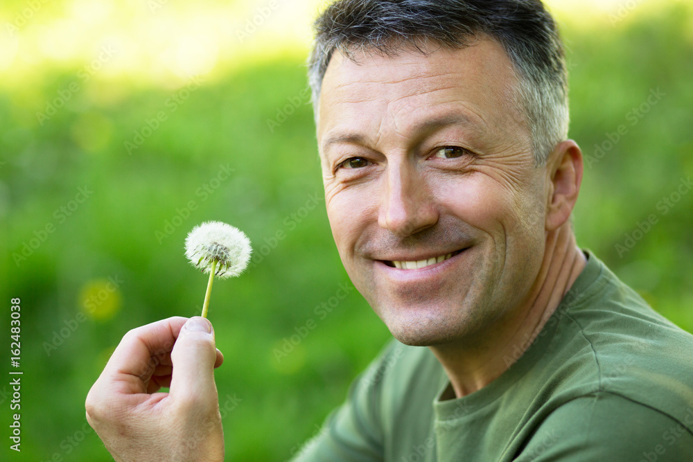 Man with dandelion over blured green grass, summer nature outdoor Man with dandelion over blured green grass, summer nature outdoor