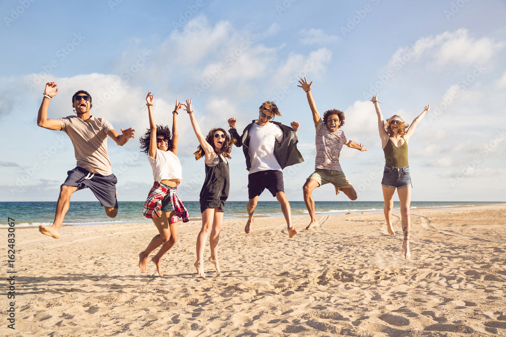 Portrait of excited young friends jumping - obrazy, fototapety, plakaty 