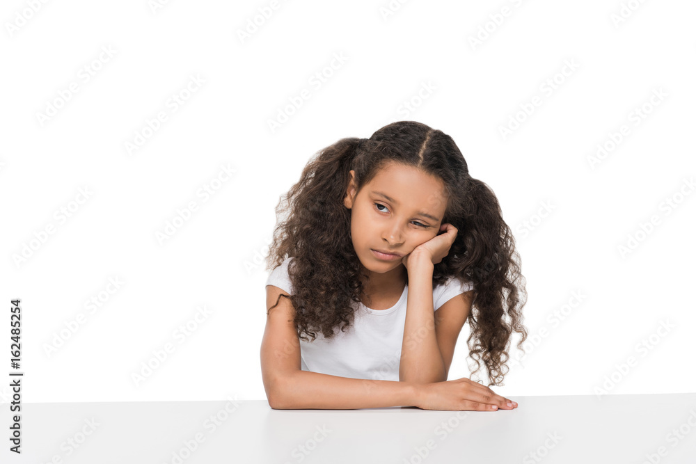 Portrait of bored little girl sitting at table and looking away isolated on white Portrait of bored little girl sitting at table and looking away isolated on white