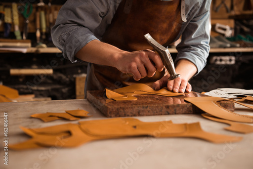 Close up of a shoemaker man working with leather photo