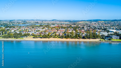 Aerial view on sunny beach with residential suburb on the background. Auckland, New Zealand.