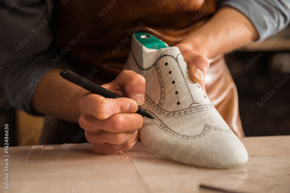 Close up of a male shoemaker drawing design - obrazy, fototapety, plakaty 