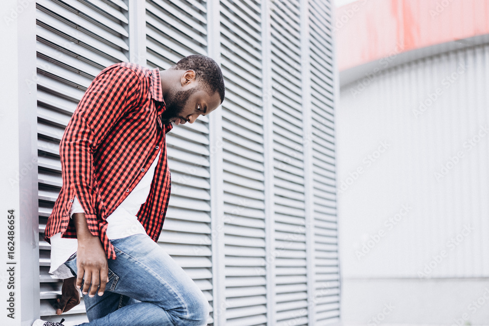 Handsome Afro American man wearing casual clothes in modern city leaning on the wall
