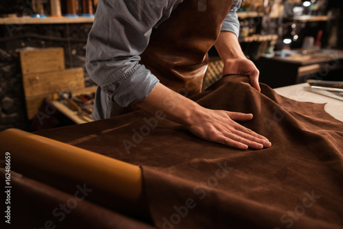 Close up of a cobbler working with leather textile photo