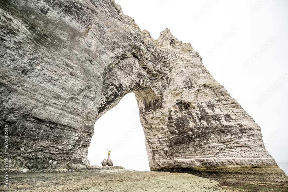 Landscape view on the huge stone cliff with a hole and traveler standing inside