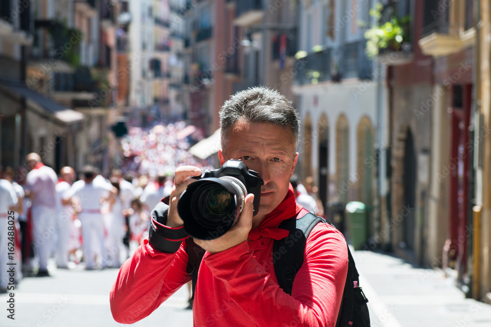 Photographer on San Fermin. Photojournalist. People celebrate San Fermin festival in traditional white and red clothing with red necktie, 06 July 2016, Pamplona, Navarra, Spain.