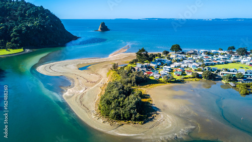 Aerial view on a river mouth with residential suburb on the shore and ocean with small islands on the background. Auckland, New Zealand