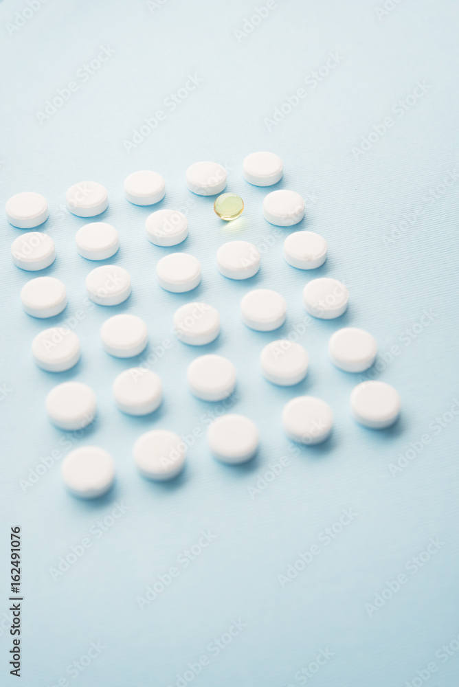 One liquid capsule in a pattern of white tablets