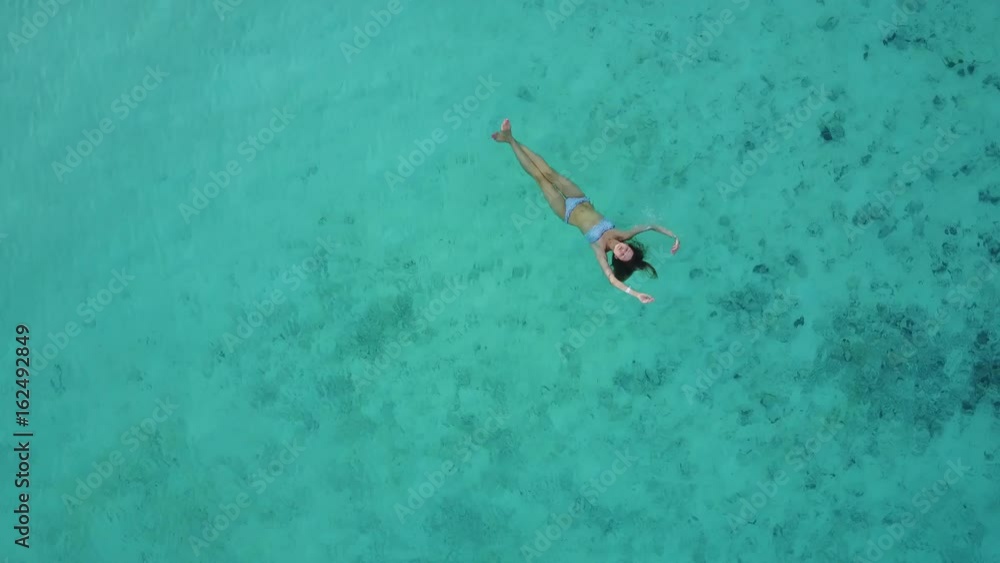 Aerial view of an attractive woman in a bikini floating in crystal clear sea. Pretty beatifull girl swimming in Indian ocean. Drone 4k footage. Aerial view of an attractive woman in a bikini floating in crystal clear sea. Pretty beatifull girl swimming in Indian ocean. Drone 4k footage.