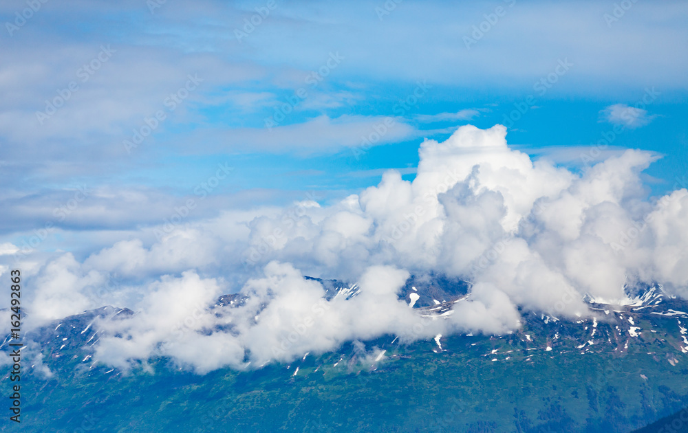 Alaskan Mountains in Clouds Under Blue Sky